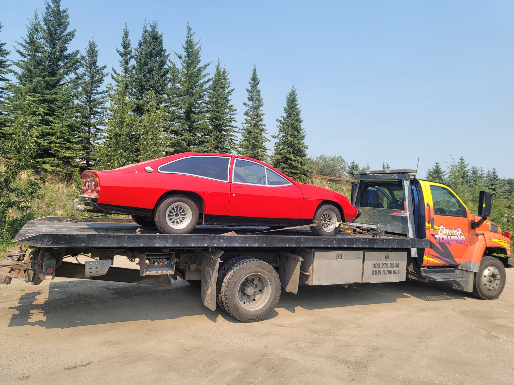 Classic red coupe transported on flatbed tow truck – Calgary