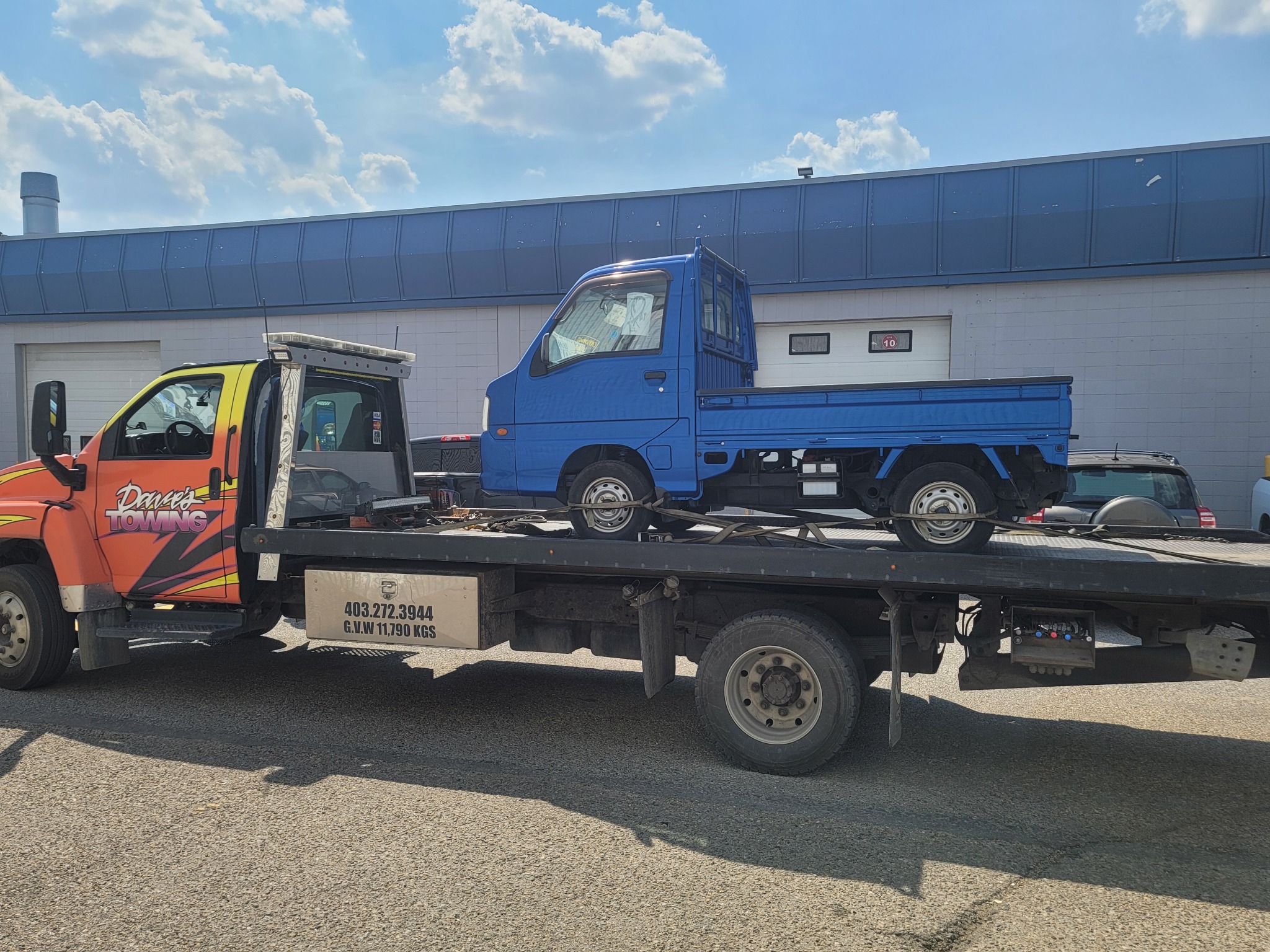 Flatbed towing a compact utility truck in Calgary (NE)